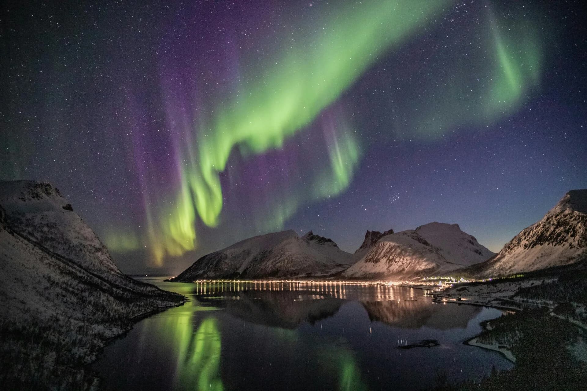 Auroras Boreales danzando sobre montañas y agua en Noruega