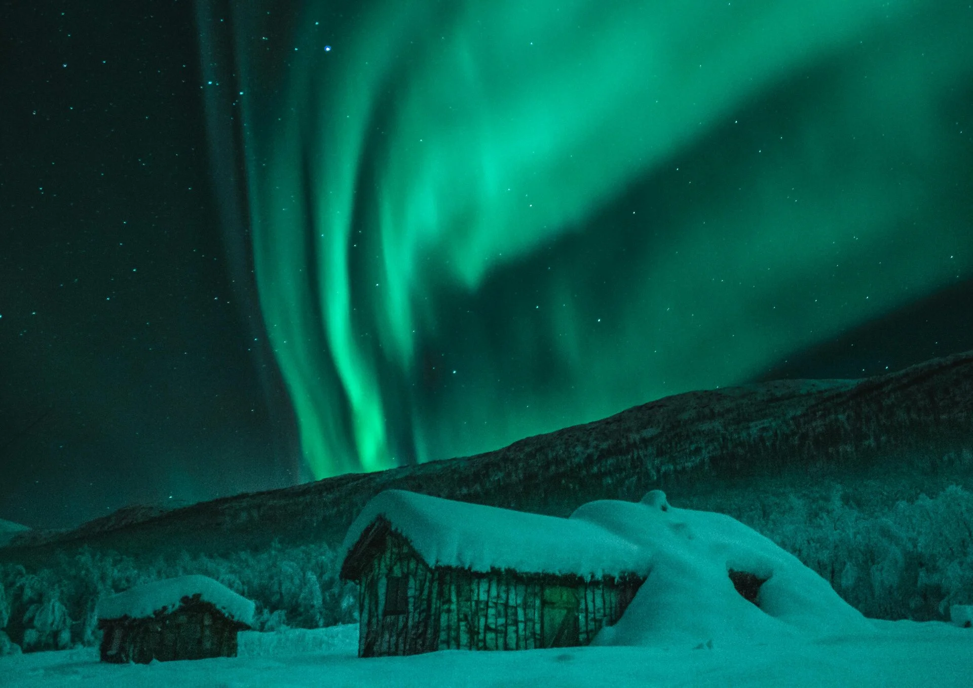Aurora boreal con colores verdes intensos sobre paisaje nevado