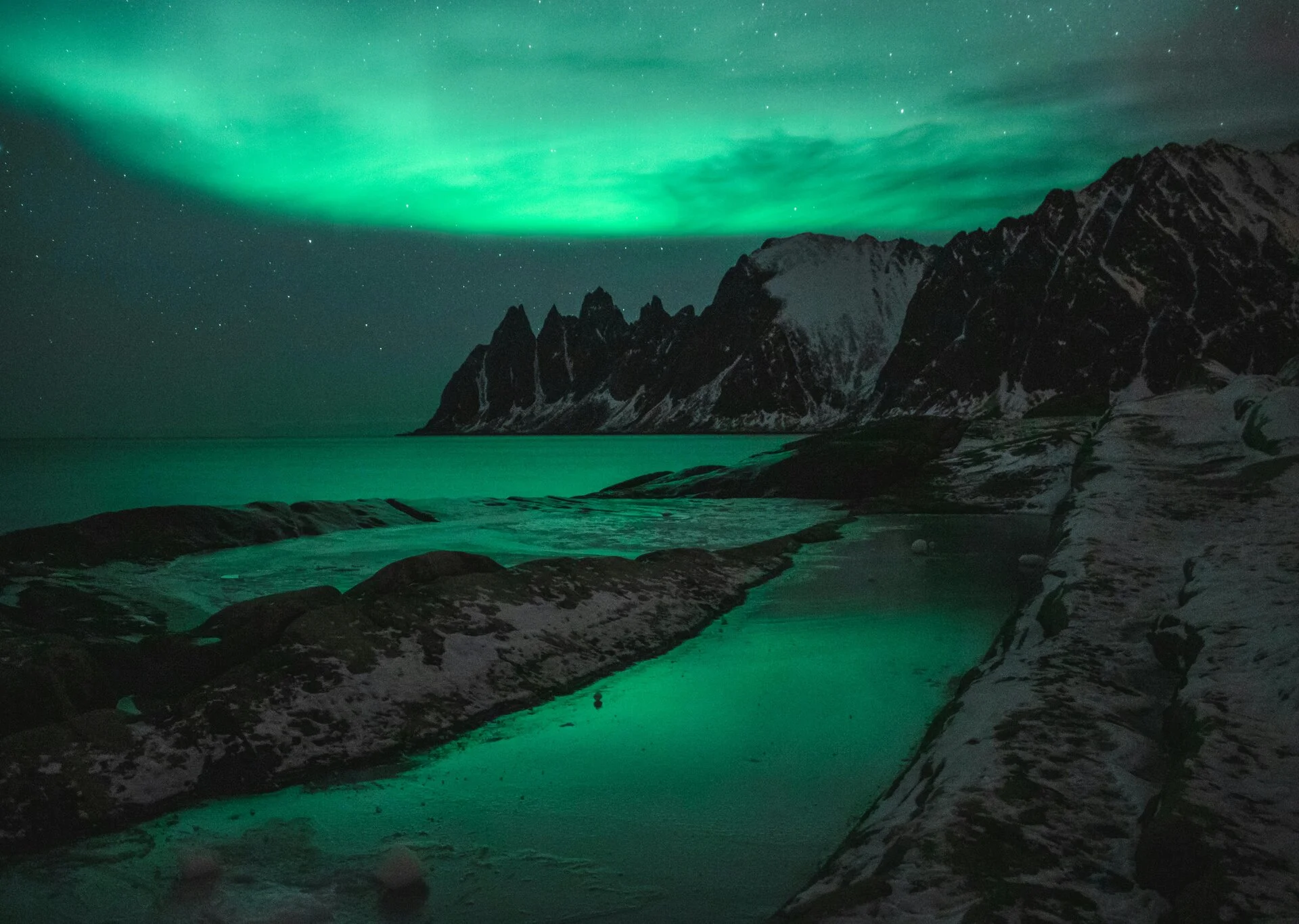 Montañas rocosas bajo el cielo nocturno con auroras